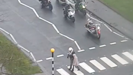 Biker helps old lady across road